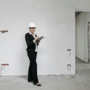 Woman in hard hat reviews notes at a construction site, examining progress.