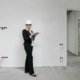 Woman in hard hat reviews notes at a construction site, examining progress.